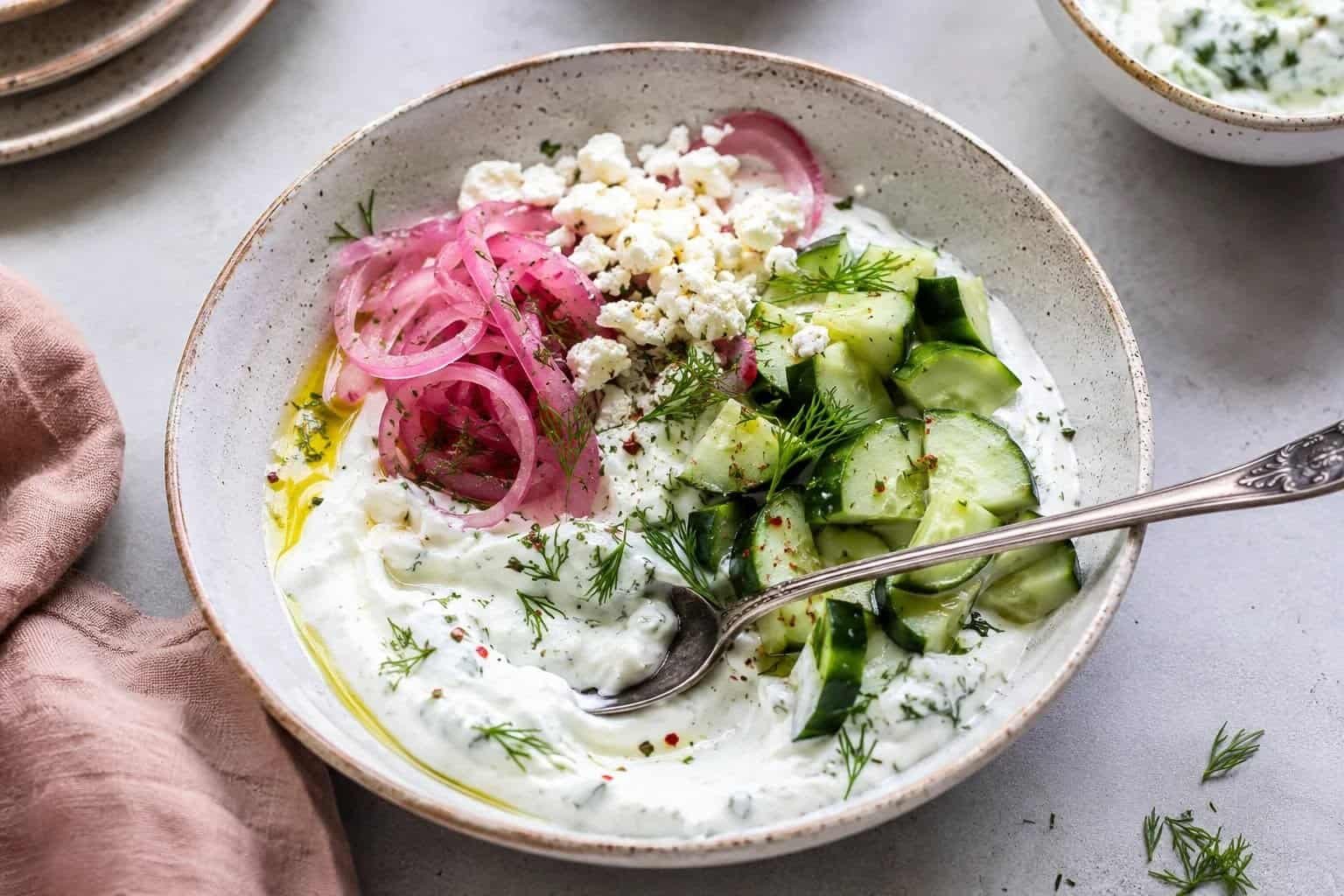 Cucumber and yogurt salad with herbs and feta cheese in a bowl.